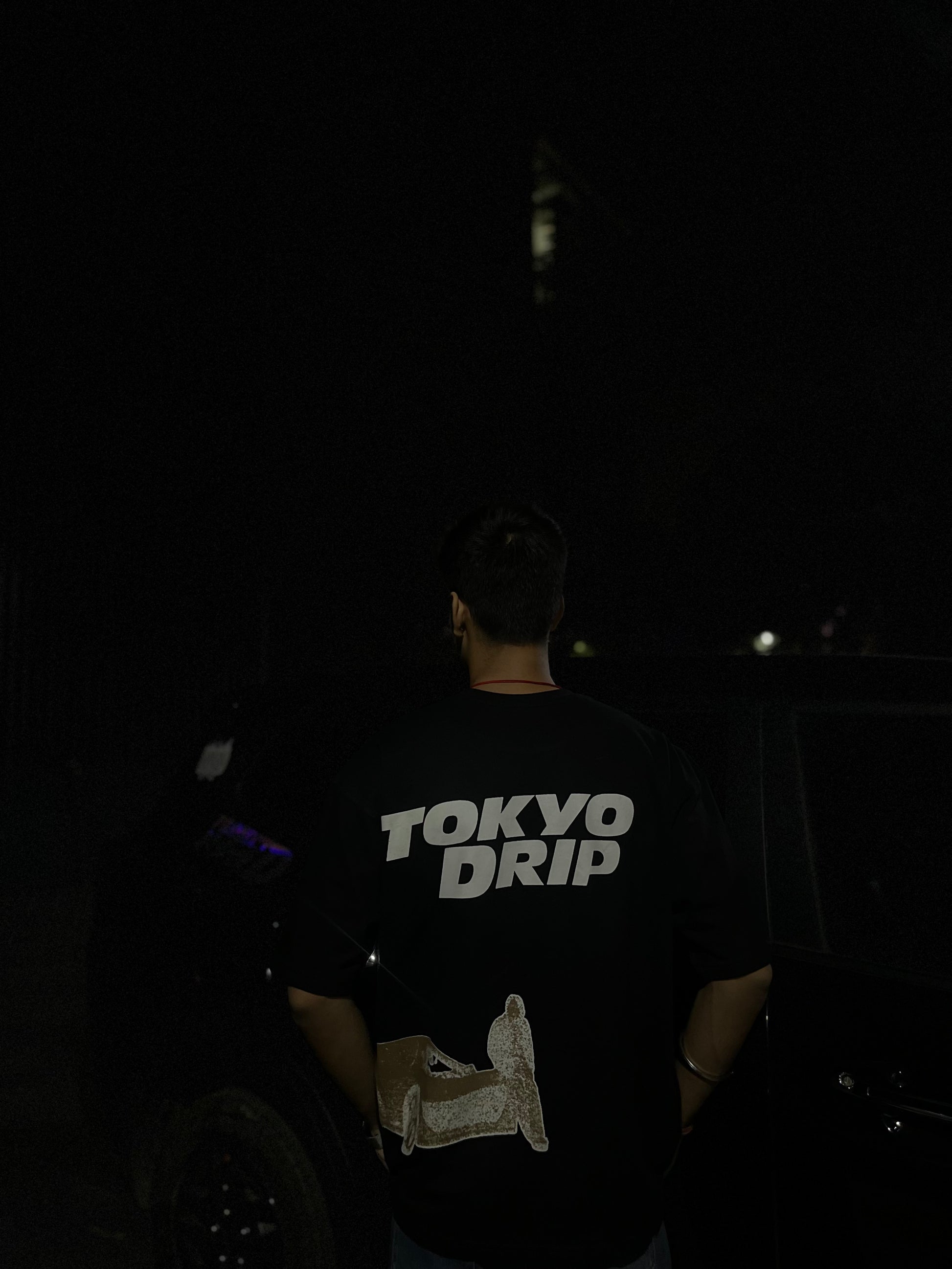 Person wearing a 'Tokyo Drip' shirt in a dark setting